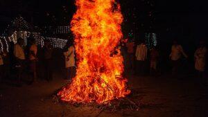 Image of bonfire with people milling about in the background