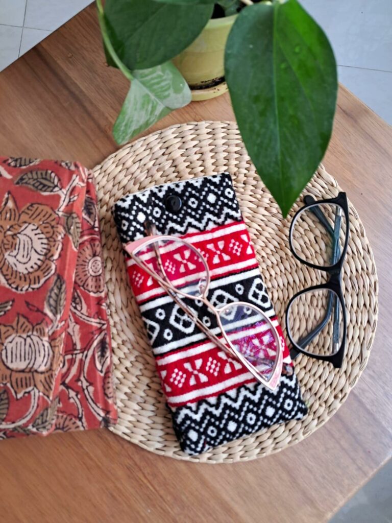 A red and white specs case is on a natural beige straw coaster, on a table. Top angle shot.