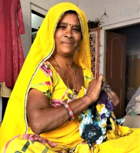 Rajasthani woman in yellow traditional wear removing the ties from the shibori cloth.