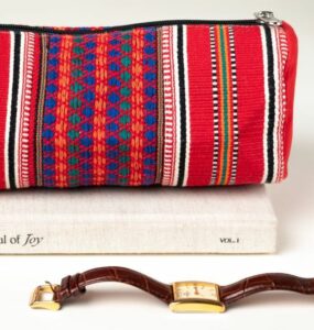 Close up of a pouch, red, with multicolour woven designs up close