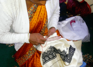 A Toda woman embroidering on cloth.
